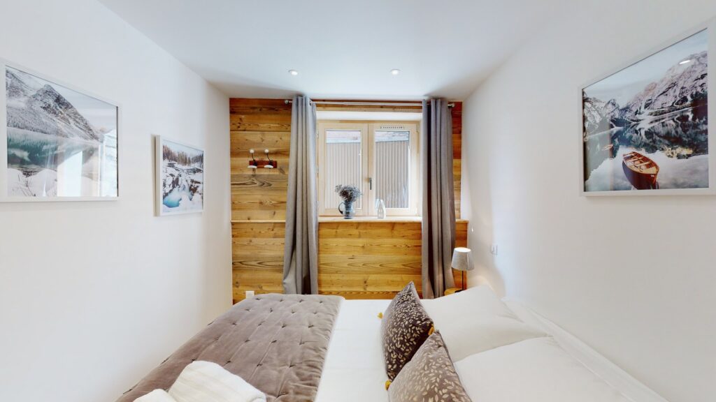 Hauptschlafzimmer der Lodge Alouette mit Doppelbett, Naturholz, edler Bettwäsche und alpiner Dekoration