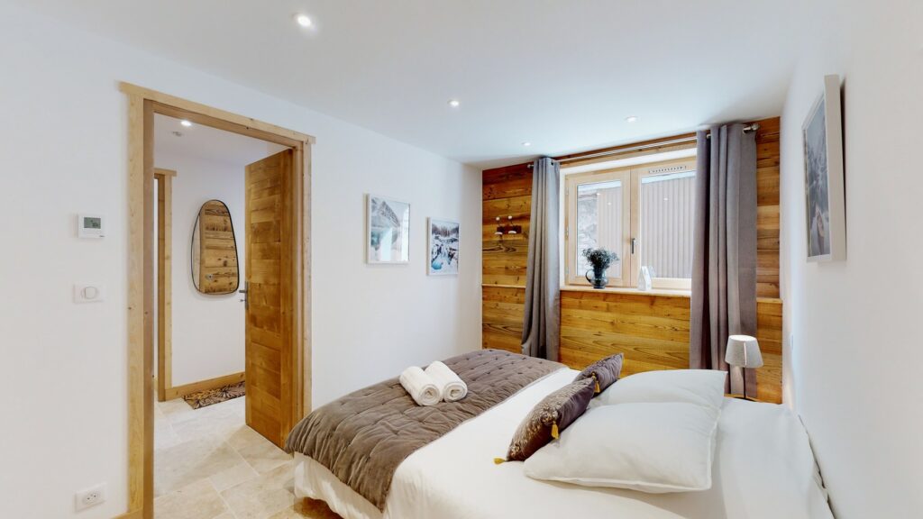 Helles Hauptschlafzimmer in der Lodge Alouette mit Doppelbett, weißer Bettwäsche und Holzverkleidung