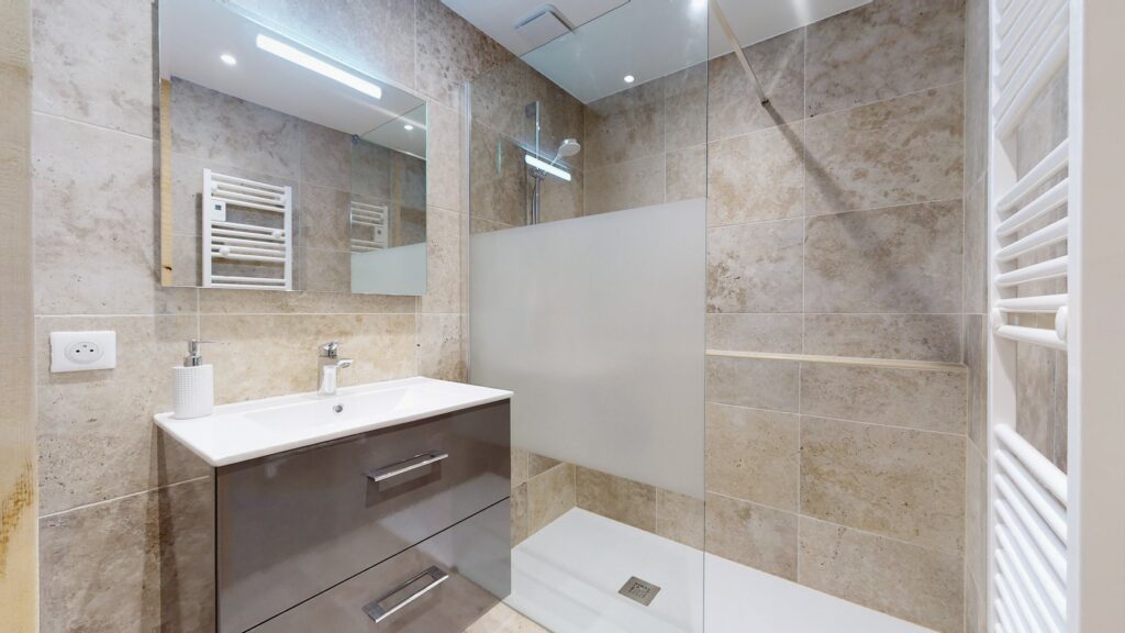 Das Badezimmer in der Lodge Alouette verfügt über eine große, verglaste Dusche, ein Waschbecken und einen Handtuchwärmer.