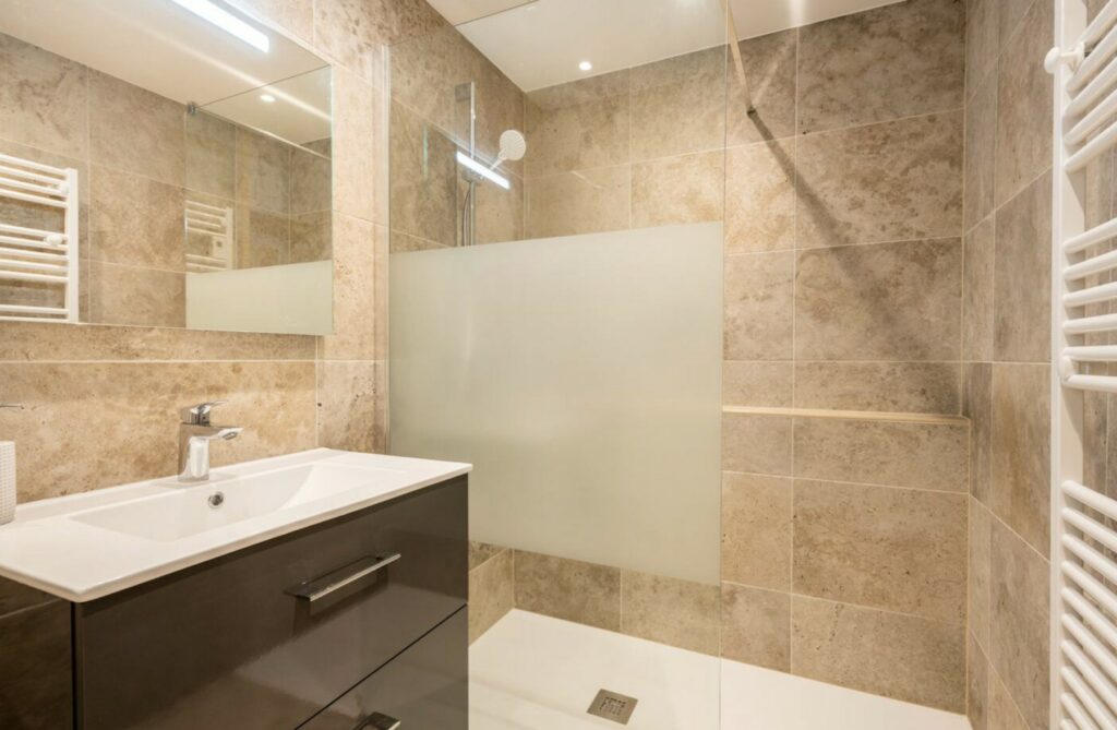 Das Badezimmer der Alouette Lodge verfügt über eine Glasdusche, Mineralfliesen und einen modernen Waschtisch.