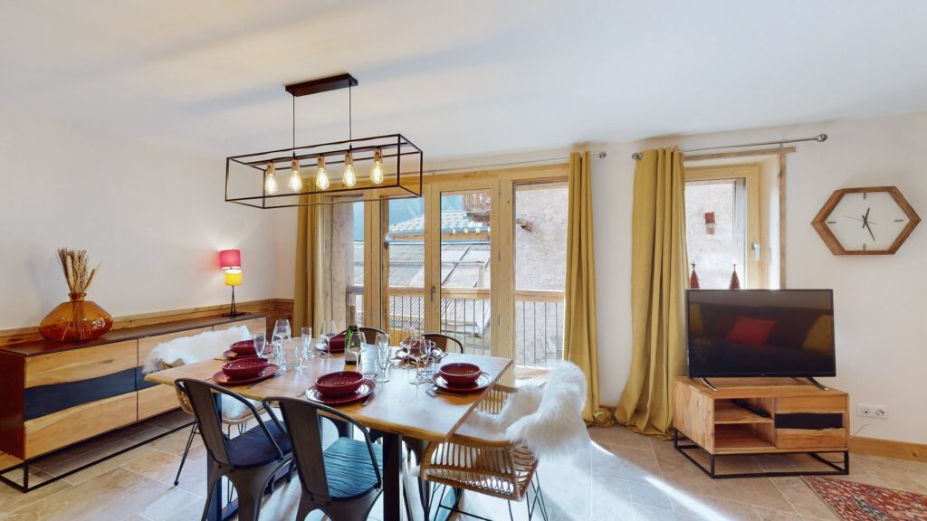 Speisesaal der Alouette Lodge mit einem für sechs Personen gedeckten Tisch, großen Fenstern und Fernseher