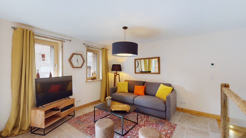 Die komfortable Lounge der Lodge Alouette bietet ein Sofa, einen Fernseher, einen warmen Teppich und eine moderne alpine Einrichtung.